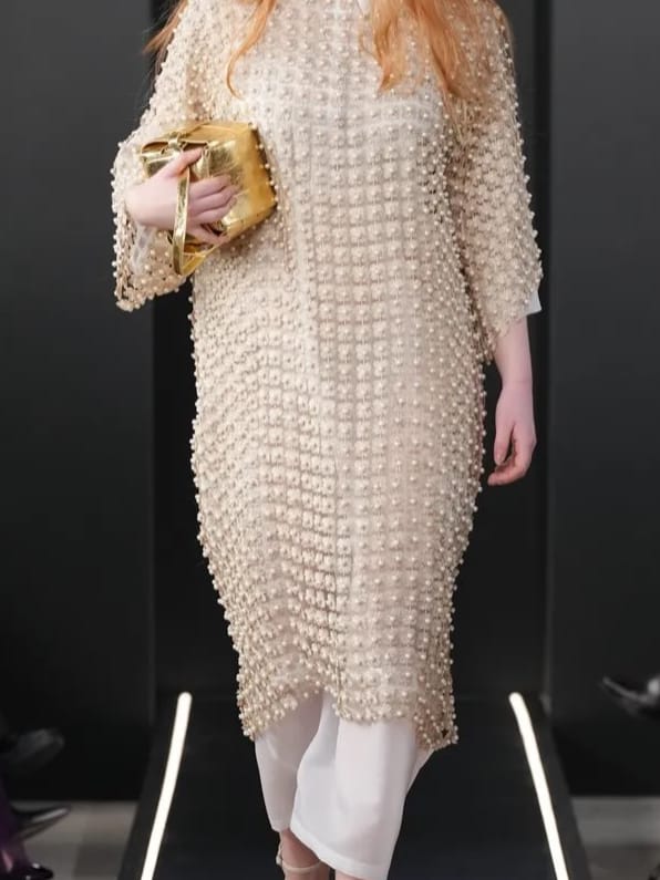 Detail des perlenbesetzten Kleids von Tokyo James mit goldener Clutch, getragen von Miriam Rochholz auf der Milan Fashion Week